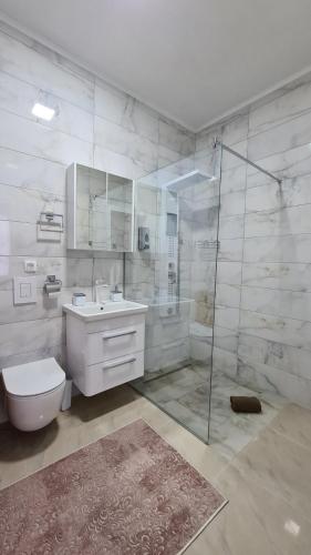 a bathroom with a shower and a toilet and a sink at Apartman Orange in Bugojno
