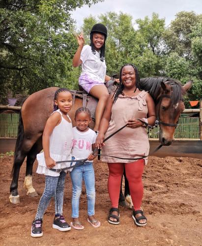 two women and two girls standing next to a horse at Die Plasie on-suite rooms in Hartbeespoort