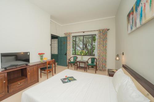 a bedroom with a bed and a desk and a television at Dana Pearl Riverside Condotel in Da Nang