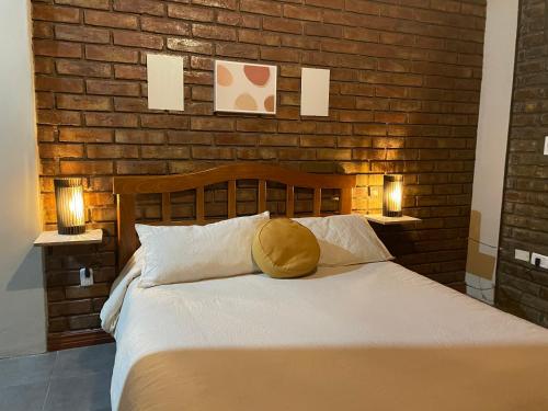 1 dormitorio con 1 cama con pared de ladrillo en Andes cerros departamento en mendoza ciudad en El Challao