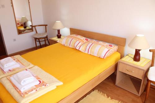 a small bedroom with a yellow bed and a chair at Guest House Tomanovic in Herceg-Novi