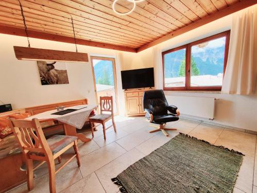 sala de estar con mesa, sillas y TV en Schickster Sky Lodge, en Leutasch