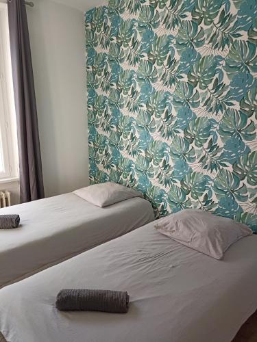 a room with two beds and a wall with a floral wallpaper at Centre in Brest