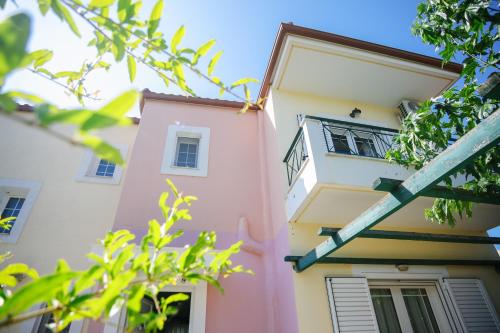 a pink and white building with trees in the foreground at Nous Dios in Xilokéra