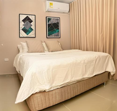 een slaapkamer met een groot bed met witte lakens bij De estreno, nuevo apto en Barranquilla in Barranquilla