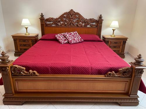 a bedroom with a large wooden bed with red sheets and pillows at Selinunte Street House in Castelvetrano Selinunte
