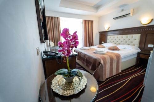 a hotel room with a bed and a table with a flower at Marina Bay Beach Mamaia Nord in Mamaia Sat/Năvodari