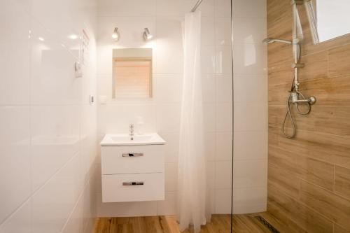 a white bathroom with a shower and a sink at Havana Sarbinowo in Sarbinowo