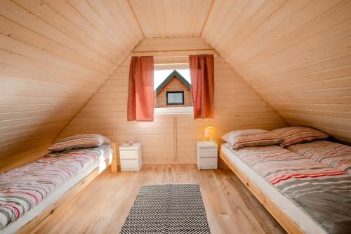 two beds in a wooden room with a window at Havana Sarbinowo in Sarbinowo