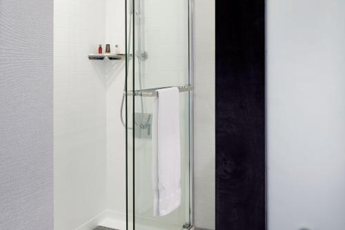 una doccia con porta a vetri e asciugamano di Marriott Cincinnati North a West Chester