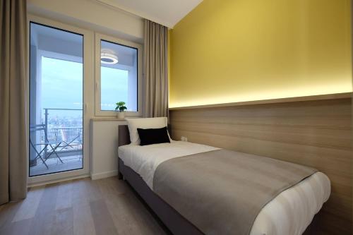 a bedroom with a bed and a large window at Apartamenty Centrum in Białystok