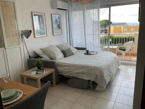 Cette chambre comprend un lit, une table et un canapé. dans l'établissement Studio le Vue mer Accès direct à la plage Parking privé Clim belle terrasse, au Grau-du-Roi