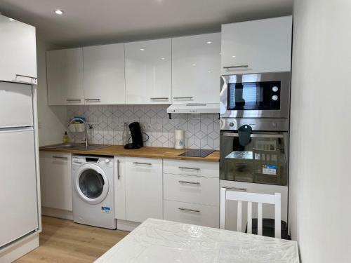 une cuisine avec des armoires blanches et une laveuse et une sécheuse dans l'établissement Appartement Les Amethystes 2, à Le Mont-Dore