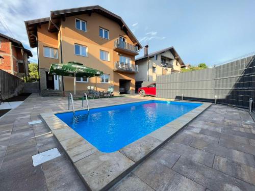 una piscina con sombrilla frente a un edificio en Summer house LejHana, en Bihać