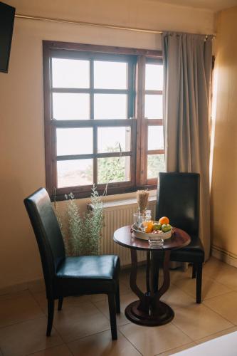 a table and two chairs with a table and a window at Pliades Traditional Guesthouse in Palaios Panteleimon