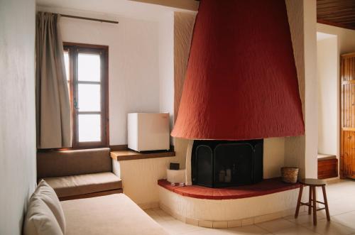 sala de estar con chimenea y techo rojo en Pliades Traditional Guesthouse en Palaios Panteleimon