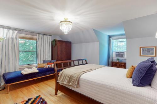 1 dormitorio con cama, banco y ventanas en Meadowhawk Haven, en Bath