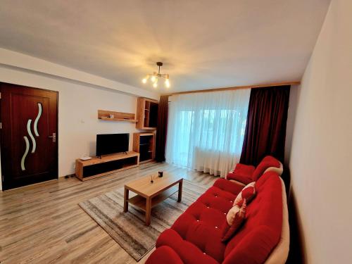 a living room with a red couch and a table at Maribelle Appartments in Târgovişte