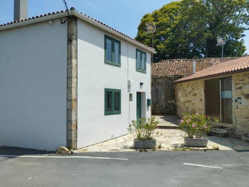 una casa bianca con finestre verdi e un garage di Casa Aldea de Abaixo a Lugo