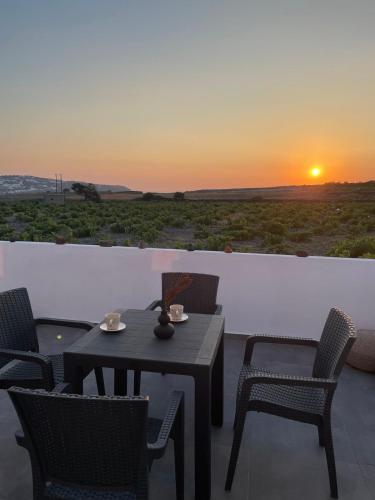 a patio with a table and chairs and a sunset at Zana's Villas-Zenia in Akrotiri