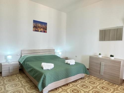 a bedroom with a green bed with towels on it at Casa panorama Sciacca in Sciacca