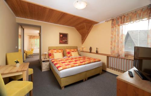 a bedroom with a bed and a desk and a window at Pension Jana - Wellness in Jilemnice