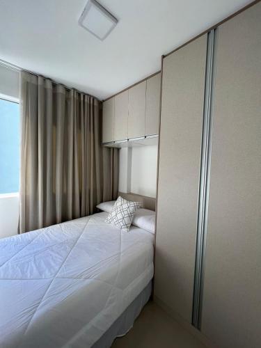 a bedroom with a large white bed with a window at Márcia Santos in Curitiba