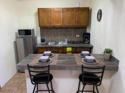 a kitchen with a counter with two chairs and a table at Casa del Carmen, hermoso departamento en Loreto in Loreto