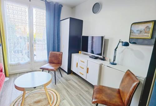 ein Wohnzimmer mit einem TV, einem Tisch und Stühlen in der Unterkunft Comfortable house 20 min to Paris with garden and BBQ in Épinay-sur-Orge