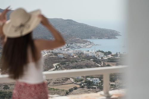 Castello Amorgos Suites في كاتابولا: فتاة صغيرة في قبعة تطل من النافذة