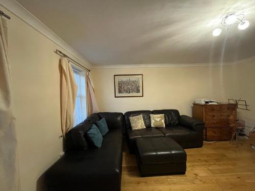 a living room with a black leather couch and a window at Beautiful big living room with sofa bed in London