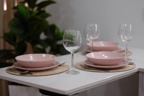 a table with pink dishes and wine glasses on it at Apartamenty Centrum in Białystok
