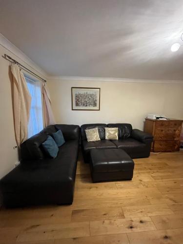 a living room with a black leather couch at Beautiful big living room with sofa bed in London