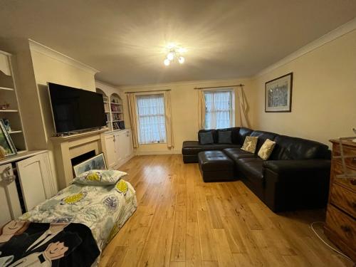 a living room with a black leather couch and a fireplace at Beautiful big living room with sofa bed in London