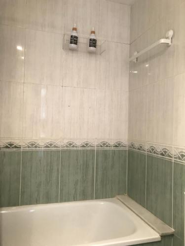 baño con bañera blanca y azulejos verdes y blancos en Apartamento Pilar, en Gandía