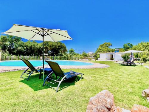 dwa krzesła i parasol obok basenu w obiekcie Villa Dafni with private pool by DadoVillas w Rodzie