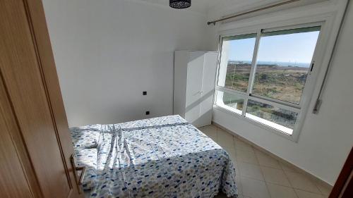 a bedroom with a bed and a large window at Appartement avec piscines, vue sur mer et accès à la plage à Achakar Hill, Tanger. in Tangier