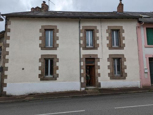 un edificio blanco con ventanas marrones en una calle en Gite de Marcella en Saint-Dizier-Leyrenne