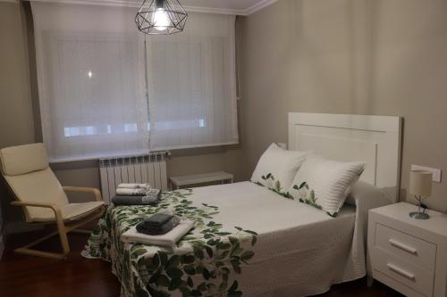um quarto com uma cama, uma cadeira e uma janela em Apartamento La Verita Santiago em Santiago de Compostela