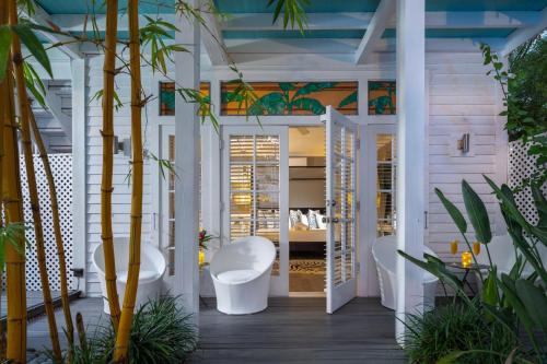 a room with white chairs and palm trees at Alexander's Gay Lesbian Guesthouse (Adult Only 21+) in Key West