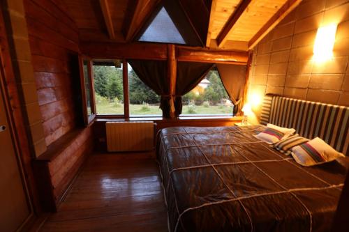 um quarto com uma cama grande num quarto com janelas em Cabaña Las Alpinas em Villa La Angostura