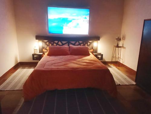 a bedroom with a bed with a flat screen tv on the wall at La casita de Manu in Guaymallen