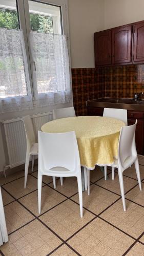 une table à manger avec des chaises blanches et une table jaune dans l'établissement Maison dans un endroit calme, à Saint-Leu-la-Forêt