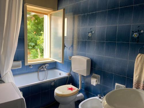 bagno piastrellato blu con servizi igienici e finestra. di Casa Adele a Sciacca