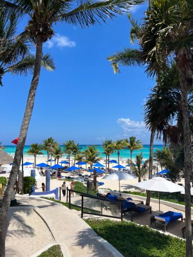 a beach with blue and white umbrellas and palm trees at The Reef Playacar Beach Resort & Spa-Optional All Inclusive in Playa del Carmen