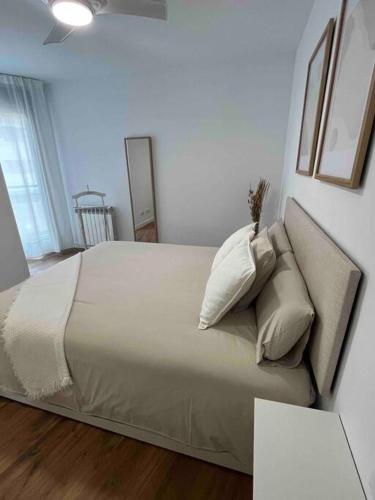 een slaapkamer met een groot bed met witte lakens en kussens bij Piso Comediantes in Albelda de Iregua