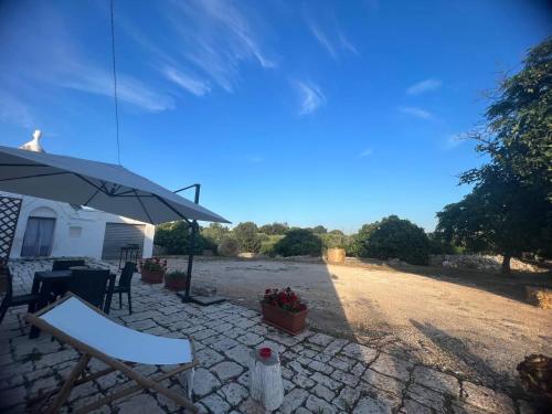 een patio met een parasol en een tafel en stoelen bij Masseria Helianthus in Ceglie Messapica