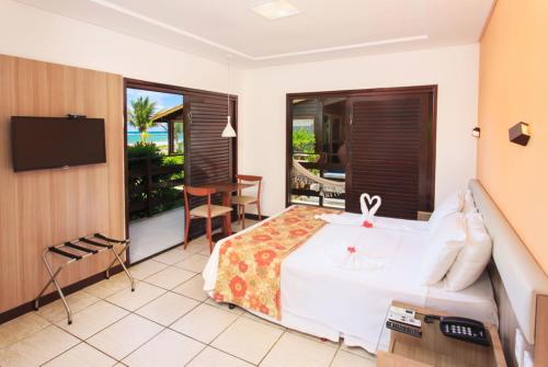 ein Hotelzimmer mit einem Bett und einem TV in der Unterkunft Pousada Canto do Porto in Porto De Galinhas