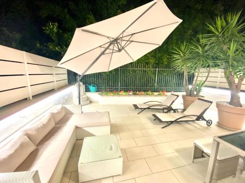 a patio with a white couch and an umbrella at Mottola Apartment in Tropea