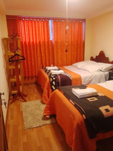 Habitación de hotel con 2 camas con sábanas de color naranja en hostal ollantaytambo apartments, en Ollantaytambo